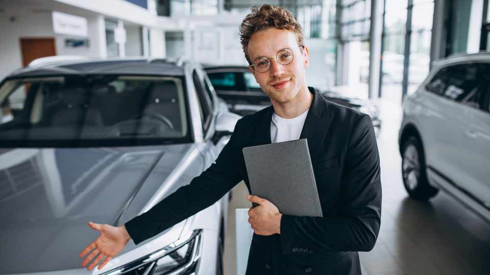Ein Verkäufer zeigt auf ein Auto und erklärt dem Kunden die Konditionen beim Auto verkaufen Magdeburg